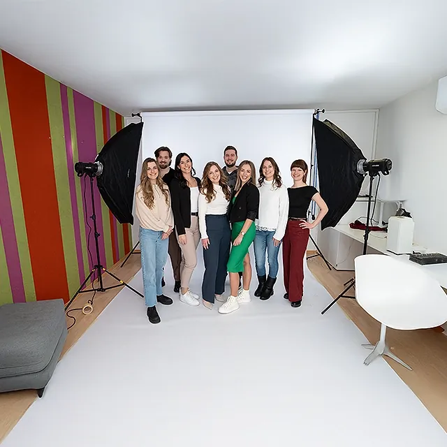 Die marketminder Julia Gorton, Viktoria Groiss, Ferdinand Schenk, Bettina Rabensteiner, Philipp Zelenka, Julia Andert, Luca Zsofia Trapp und Nataliia Karall beim On-Boarding Fotoshooting im marketmind Büro, umgeben von professionellem Equippment.