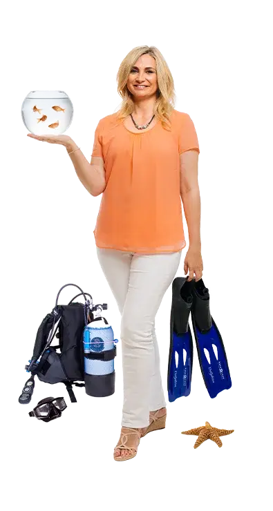 Manuela Laube hält ein rundes Aquarium mit Goldfischen in der einen und blaue Taucherflossen in der anderen Hand, mit Tauchausrüstung und Seestern zu Füssen - begeistert von der Unterwasserwelt.