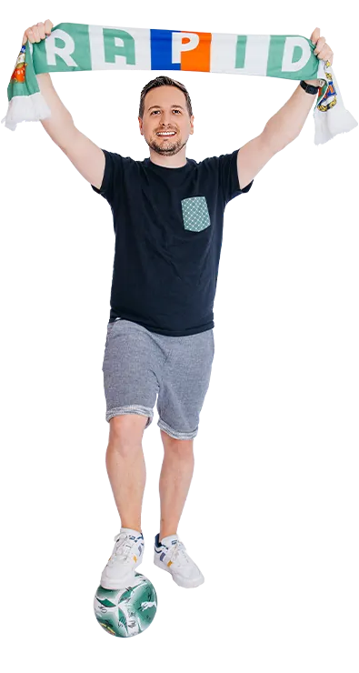 Matthias Obermeier, MSc jubelt mit einem Fussballschal und balanciert einen Ball am Fuss – sportlich, energiegeladen und voller Teamgeist.