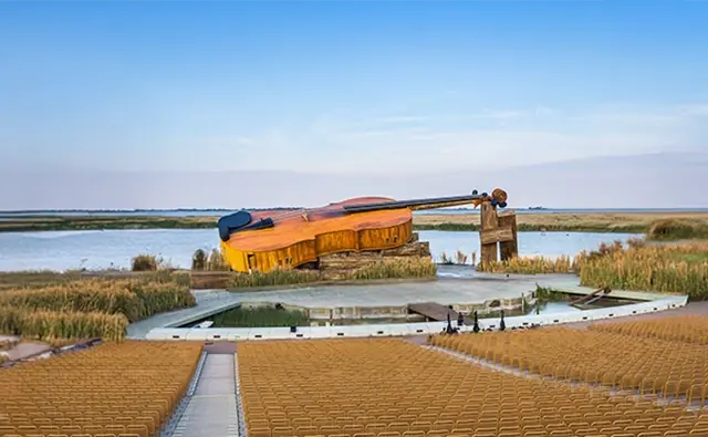 Extraordinary stage scenery at Lake Neusiedl with an oversized cello model. Symbolic image for the creative staging and international appeal of the Mörbisch Lake Festival.