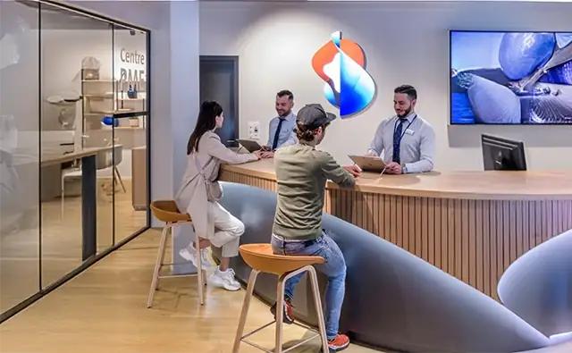 Modern Swisscom customer center where two customers sit at a counter and receive individual attention from customer advisors.