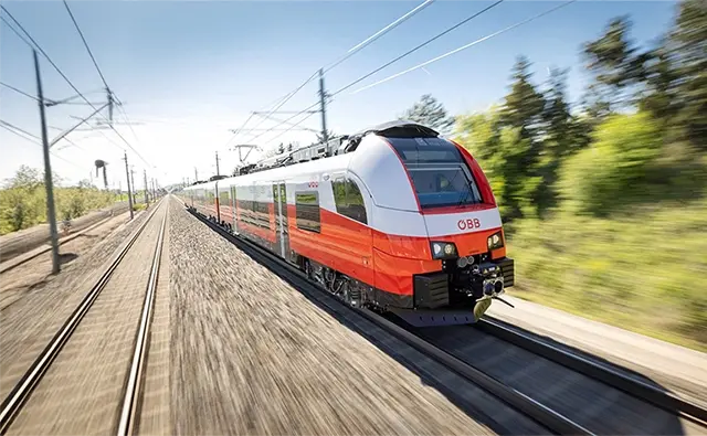 Modern ÖBB express train in full motion on an electrified railway line. Represents sustainable mobility and punctuality in Austrian rail transport.