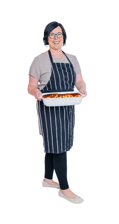 Anita Salamon wears a striped apron and proudly holds a freshly baked casserole dish in her hands - warm-hearted, pleasure-loving, and with joy in cooking.