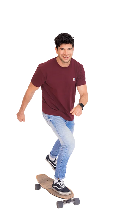 Christoph Halbertschlager rides smoothly on a longboard, smiles and wears sporty-casual jeans and shirt - full of dynamism and fun in movement.