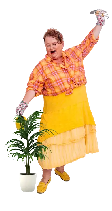 Lydia Croce dances cheerfully with rubber gloves, watering can and colorful clothing around a potted plant - vivacious, colorful, and full of humor.