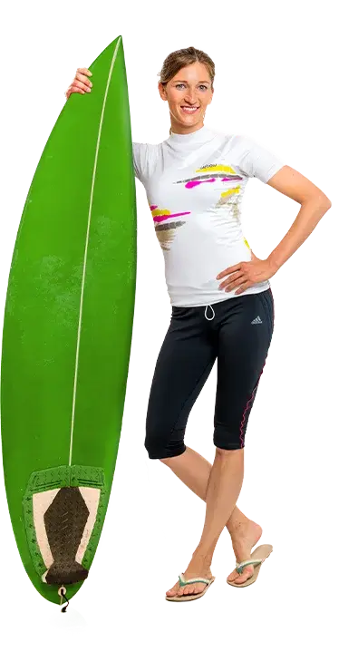 Martina Bauer, PhD leans relaxed against a large green surfboard, wears sportswear and flip-flops - ready for the next wave at the beach.