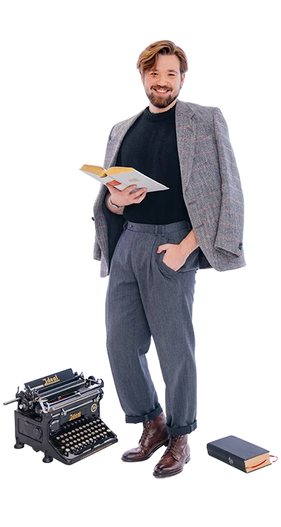 Philipp Zelenka stands elegantly with book in hand, next to him an old typewriter and another book - stylish, well-read, and with a touch of retro charm.
